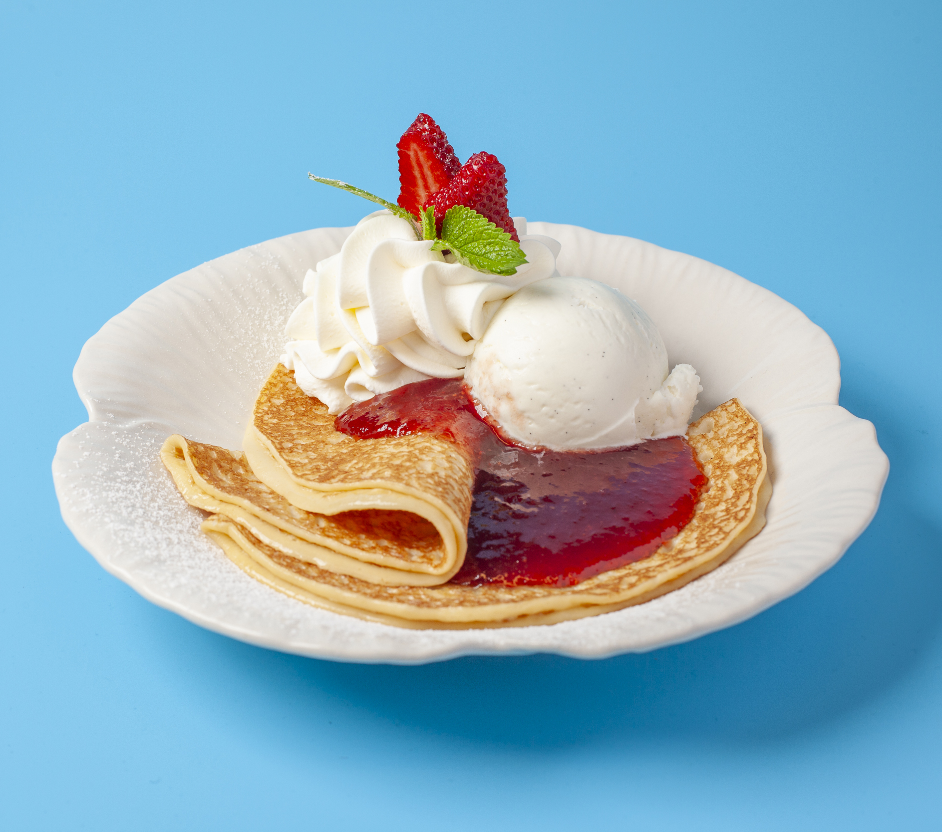 Pannkakor med vaniljglass och jordgubbssylt. Toppade med grädde och jordgubbe. Serveras i ministekpanna